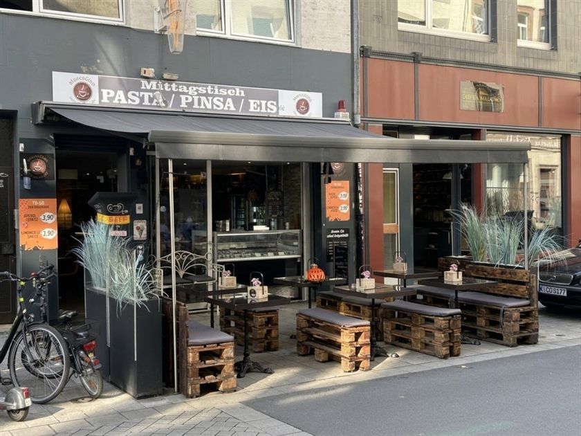 Die Terrasse des MoccaGino mit Markise, Palettenbänken und Gräsern vor dem Lokal in der Severinstraße 19 in Köln