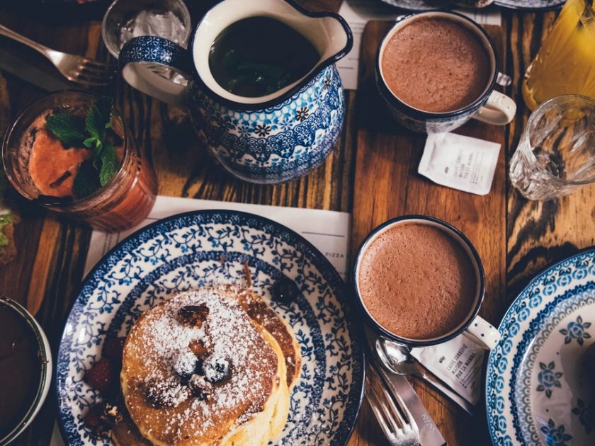 Zwei Tassen heiße Schokolade auf einem gedeckten Frühstückstisch
