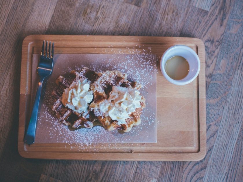 Frisch gebackene Waffel mit Puderzucker auf einem Holzbrett